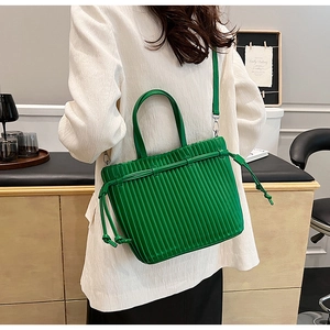 Detail view of emerald green pleated PU leather tote bag with knotted drawstring on a model