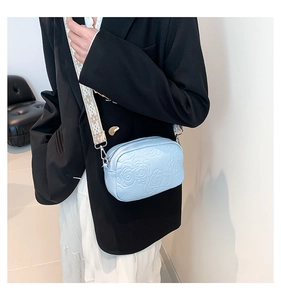 Detail view of light blue PU leather crossbody bag with rose embossing and woven strap