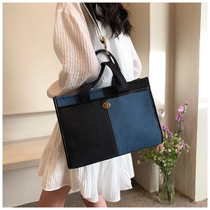 Detail of a two-tone denim tote bag with gold metal twist lock and striped shoulder strap