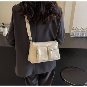 Detail of cream PU crossbody bag with dual front zipper pockets and wide shoulder strap