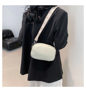 Detail of white PU camera bag with 3D rose flower embossing and woven shoulder strap