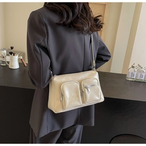 Detail of off-white glossy PU leather crossbody bag with dual zipper pockets and strap