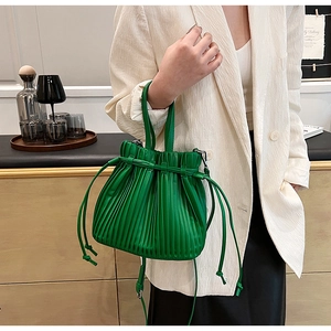 Detail view of a bright green pleated PU leather crossbody bag with drawstring closure