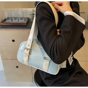 Detail of mint green and cream PU leather handbag with shoulder strap on a model