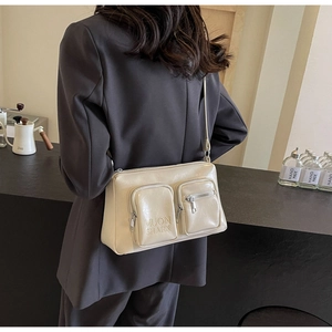 Detail of a beige glossy PU leather crossbody bag with dual pockets and metal zipper