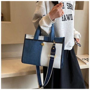 Detail view of denim patchwork tote bag with gold rotary lock and wide blue strap