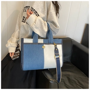 Close-up of color-block denim tote bag featuring golden turn-lock and wide shoulder strap