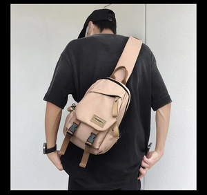 Detail of beige nylon crossbody bag featuring dual buckle closure and brand logo patch