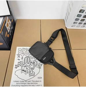 Minimalist black nylon crossbody bag with adjustable wide strap and front letter print