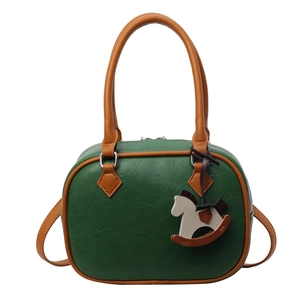 Retro dark green Boston handbag with brown handles and rocking horse charm on white background