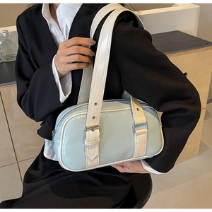 Detail view of stylish light blue PU leather boston bag with cream strap on a model