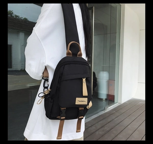 Detailed view of bicolor nylon mini backpack with buckle and logo tag on female model