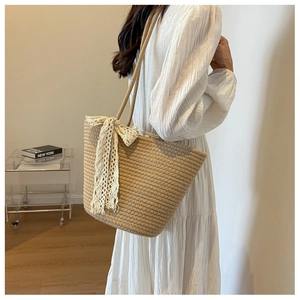 Close-up of woven shoulder bag featuring creamy white lace bow and khaki rope texture