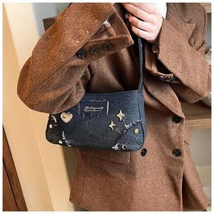 Gros plan du sac en jean avec clous en cœur argentés et détails effilochés sur blazer brun
