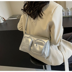 Detail of silver metallic PU crossbody bag with double front pockets and embossed logo