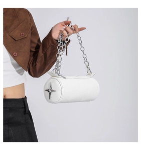 Close-up of white cylindrical PU leather bag with silver star charm and metal chain