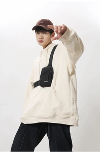 Detailed shot of a black nylon crossbody chest bag styled with a beige hoodie