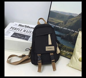 Close-up of black nylon backpack with khaki straps and brand logo on front pocket