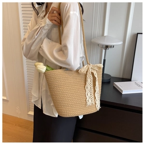 Close-up of woven straw shoulder bag with elegant white lace bow and tulip decoration