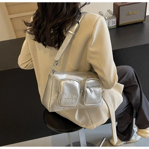 Detail of silver metallic PU shoulder bag with dual zipper pockets and glossy texture