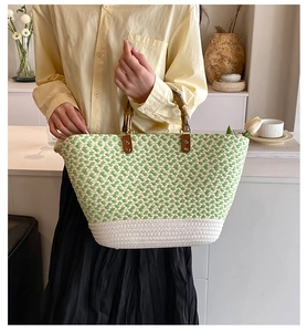 Detail of woven tote bag with green herringbone pattern and vintage bamboo handles