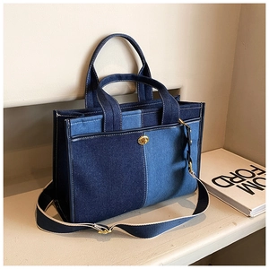 Stylish patchwork denim crossbody bag with gold buckle on minimalist display stand
