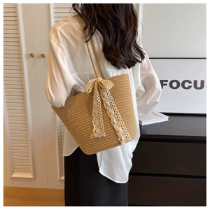 Detail of a beige woven tote bag featuring a delicate white lace bow in a chic home setting