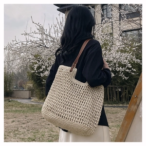 Detail of beige woven tote bag with square crochet mesh and dark brown leather straps