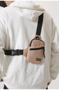 Detail view of the khaki nylon chest bag showing texture, zippers and adjustable strap