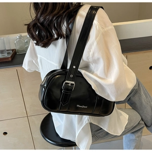 Detail of a black glossy PU leather Boston-style shoulder bag with silver metallic buckle
