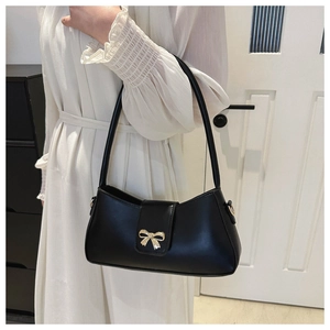 Détail montrant la boucle noeud doré sur un sac baguette en cuir noir élégant