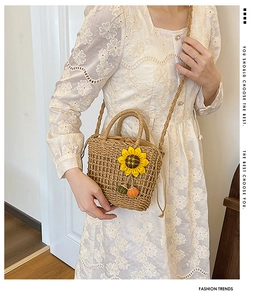 Detail of straw handbag with 3D sunflower decor and drawstring closure worn by model