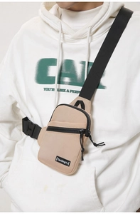 Close-up of khaki nylon chest bag with double black zippers and adjustable strap detail