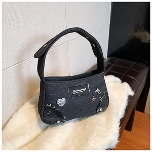 Sac à bandoulière tendance en jean avec clous argentés et écusson sur tapis blanc