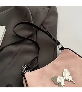 Détail du sac à bandoulière en daim rose avec boucle papillon argentée et sangle marron