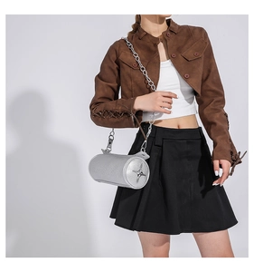 Detail view of silver cylindrical chain bag with star metal ornament on grey background