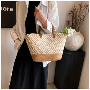 Detail of two-tone woven tote bag with bamboo handle and brown leather rivet accents