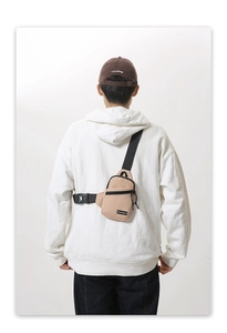 Close-up of beige nylon chest bag with black zipper detail and adjustable strap