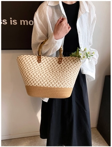 Detail of woven straw tote bag with bamboo handle and contrasting beige pattern