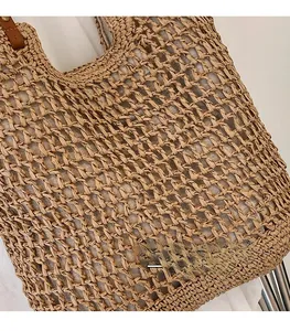 Close-up of woven straw tote bag with brown leather handles and a fabric lining