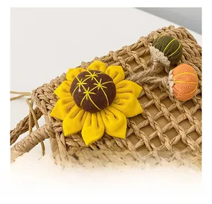 Close-up of woven straw handbag texture with knit sunflower and colorful pom-poms detail