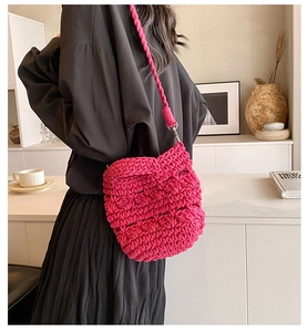 Detail of rose red knitted crossbody bag with textured crochet pattern and soft handle