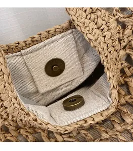 Close-up of metal magnetic snap closure on a hand-woven straw tote bag with linen lining