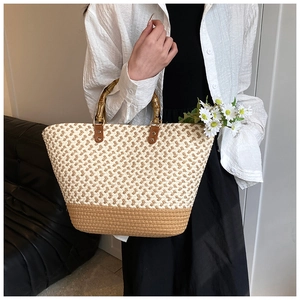 Detailed macro view of woven straw tote bag with bamboo handle and dual-tone texture
