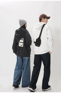 Rear view of couple wearing minimalist nylon crossbody chest bags in black and cream white