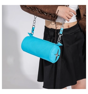 Detail of light blue cylinder bag with lychee texture and silver star logo on model