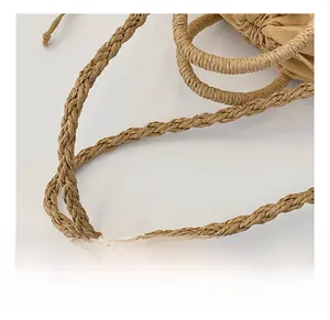 Detailed macro view of the woven khaki shoulder strap on a straw handbag