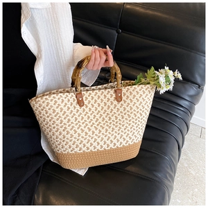 Detailed view of handmade woven straw tote bag with bamboo handles and daisy ornament