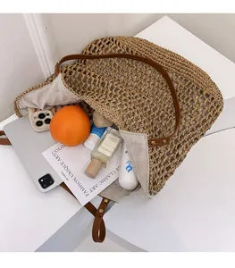 Detail view of woven straw tote bag showing brown leather handles and large capacity interior