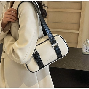 Detail view of cream PU leather shoulder bag with black straps and brand lettering